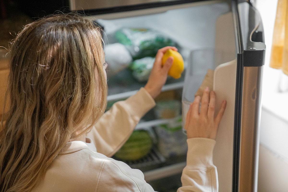 woman getting a lemon from a refrigerator