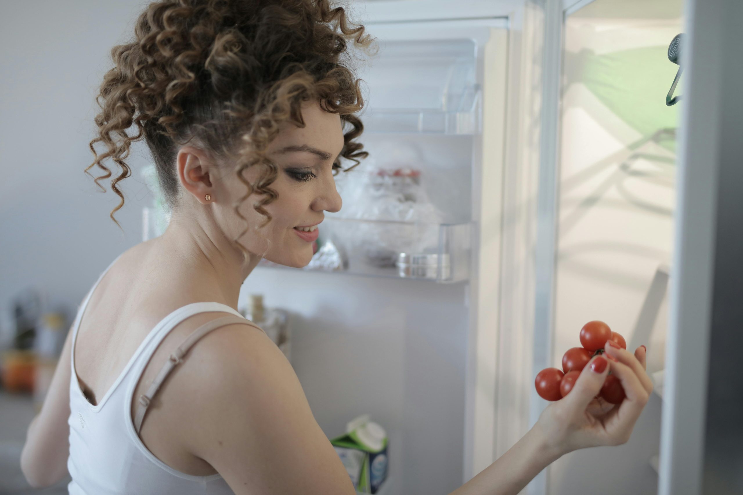 woman getting red grapes from a refrigerator